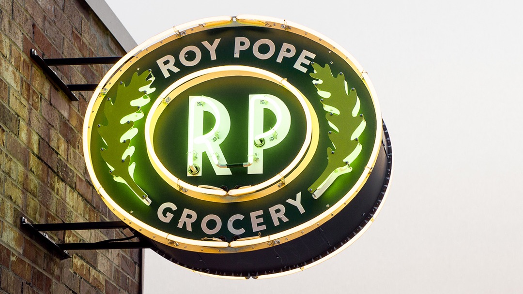 Roy Pope Grocery's round neon sign on its brick exterior